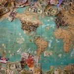 world map with currencies from all around the world laying on it